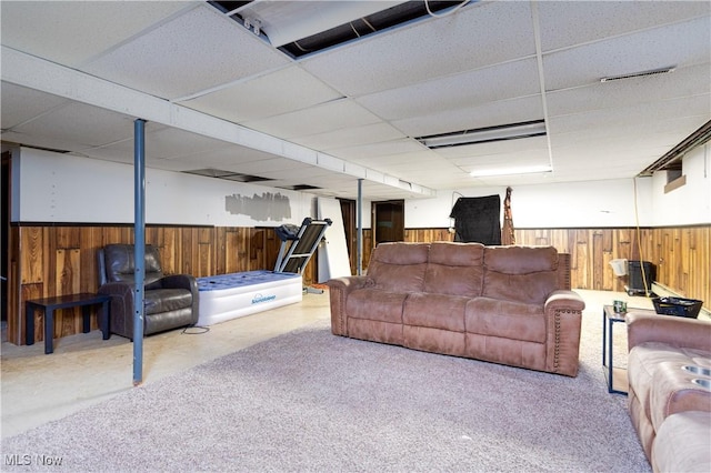 living room featuring wooden walls and a paneled ceiling