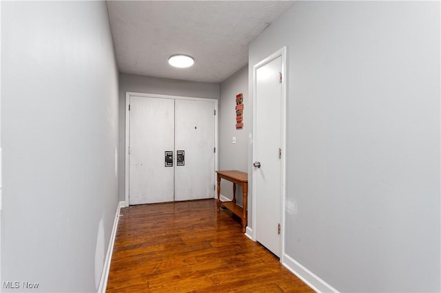 corridor with dark hardwood / wood-style flooring and a textured ceiling