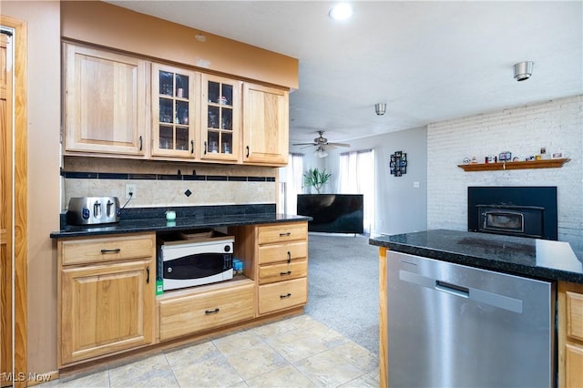 kitchen with light brown cabinetry, tasteful backsplash, light carpet, dark stone countertops, and dishwasher