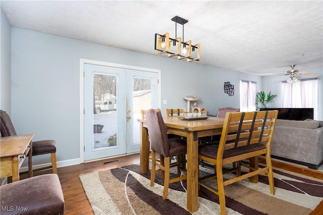 dining area featuring dark hardwood / wood-style flooring, a chandelier, french doors, and a textured ceiling