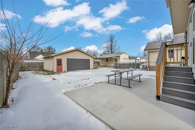 snow covered patio with a garage and an outbuilding