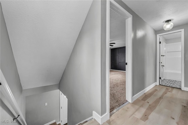 hallway with light hardwood / wood-style flooring and a textured ceiling