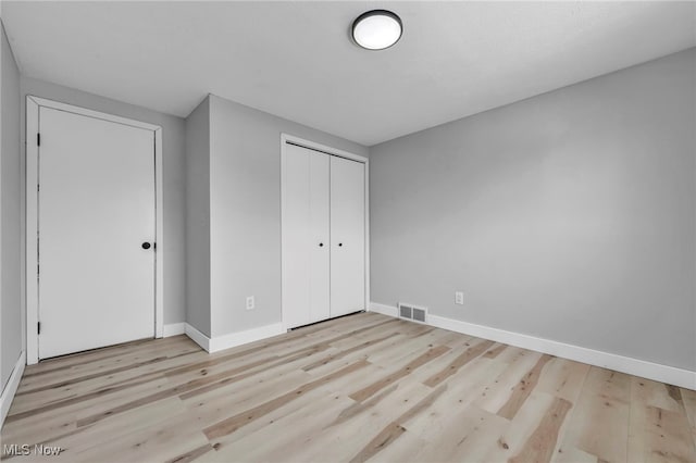 unfurnished bedroom featuring a closet and light hardwood / wood-style flooring