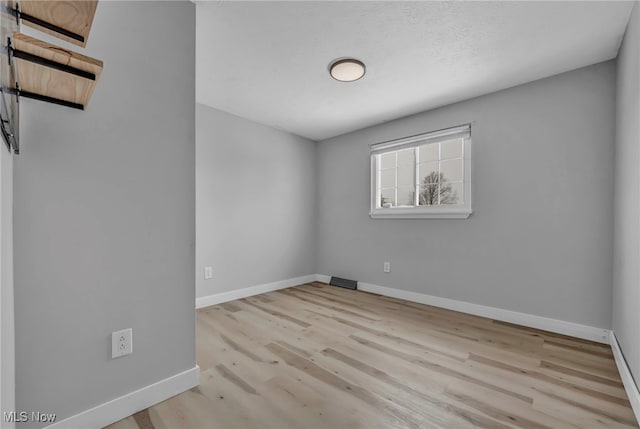 unfurnished room with a textured ceiling and light hardwood / wood-style flooring