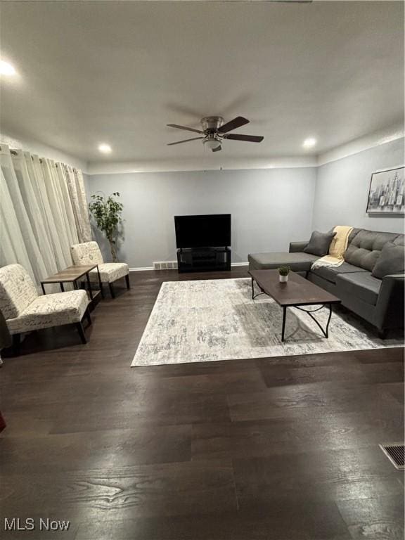 living room featuring dark wood-type flooring and ceiling fan