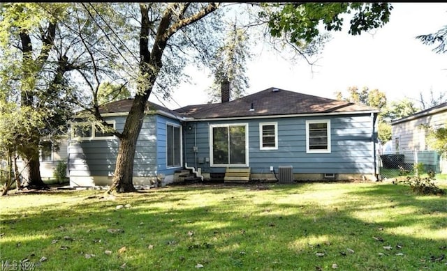 rear view of house with cooling unit and a yard