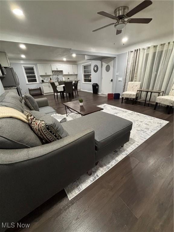 living room featuring ceiling fan and dark wood-type flooring