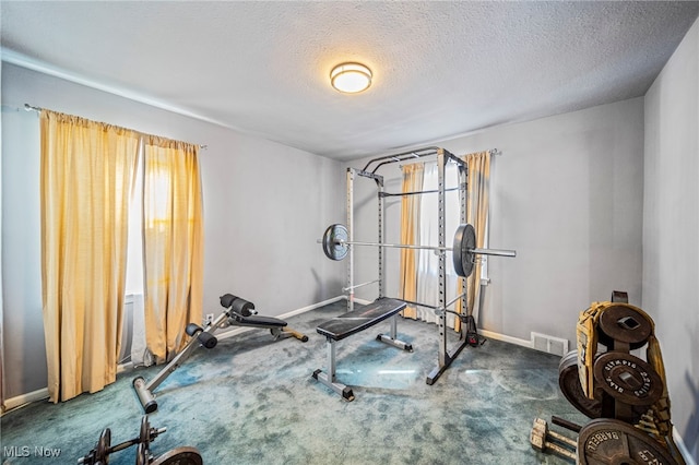 exercise room featuring a textured ceiling and dark carpet