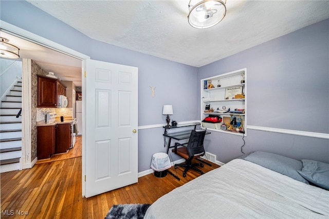 bedroom featuring dark hardwood / wood-style floors, a textured ceiling, and white refrigerator