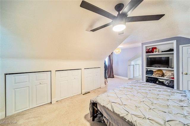 bedroom featuring vaulted ceiling, carpet floors, two closets, and ceiling fan