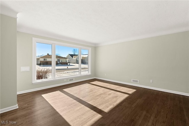 empty room with ornamental molding, dark hardwood / wood-style flooring, and a textured ceiling