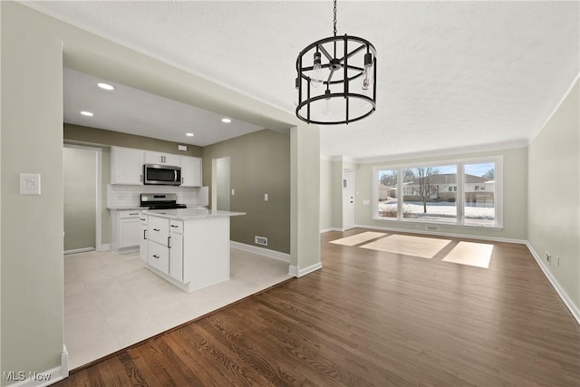 kitchen with white cabinetry, backsplash, stainless steel appliances, decorative light fixtures, and light wood-type flooring