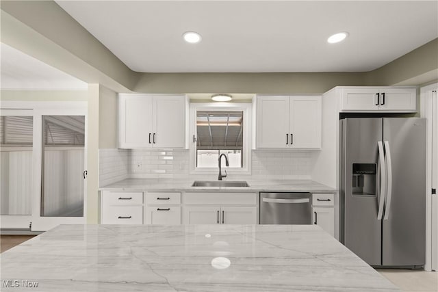 kitchen featuring white cabinetry, sink, light stone counters, and stainless steel appliances