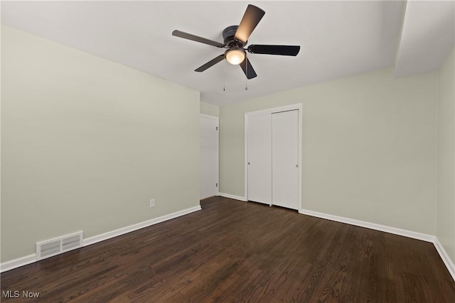 unfurnished bedroom featuring dark wood-type flooring, ceiling fan, and a closet