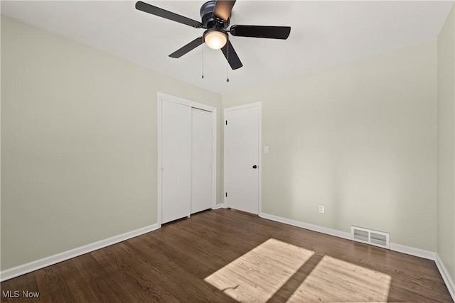 unfurnished bedroom featuring ceiling fan, dark hardwood / wood-style flooring, and a closet