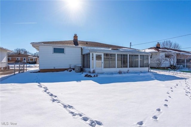 snow covered back of property featuring cooling unit and a sunroom