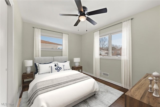 bedroom featuring hardwood / wood-style flooring, ceiling fan, and multiple windows