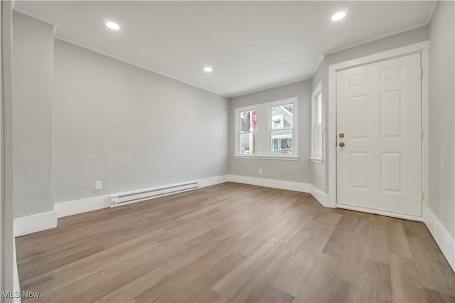 foyer entrance featuring a baseboard heating unit, crown molding, and light hardwood / wood-style floors