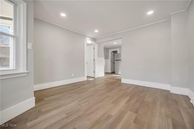 spare room with crown molding and light wood-type flooring