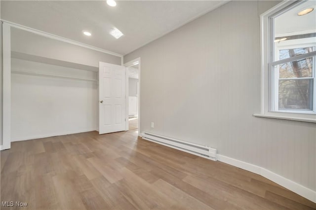 unfurnished bedroom with a baseboard radiator, light hardwood / wood-style floors, and a closet