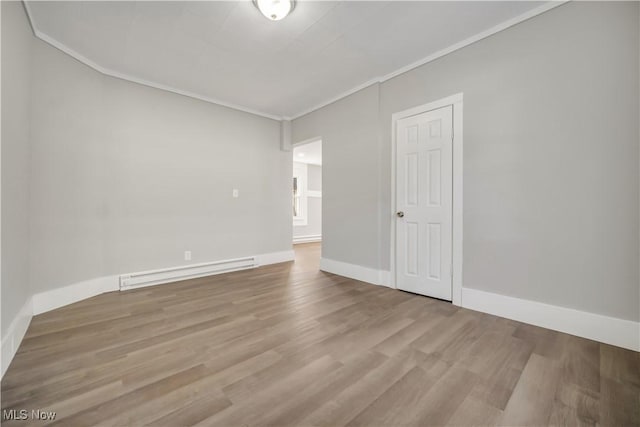 empty room with hardwood / wood-style flooring, a baseboard radiator, and crown molding