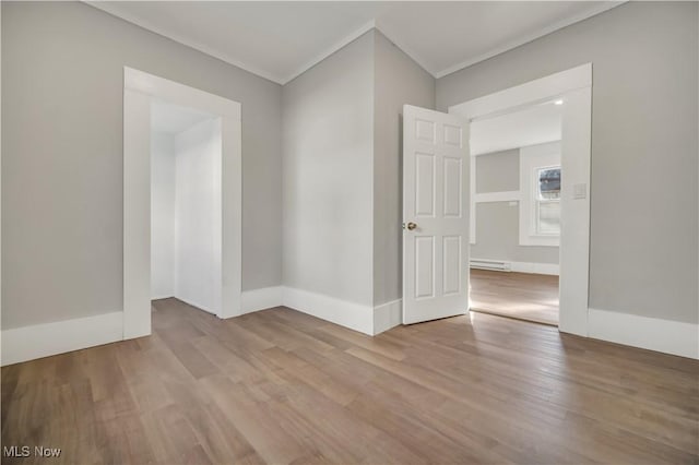 unfurnished room featuring a baseboard heating unit, crown molding, and light hardwood / wood-style floors