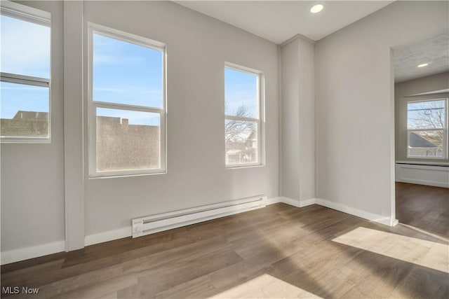 empty room with dark hardwood / wood-style flooring and a baseboard heating unit