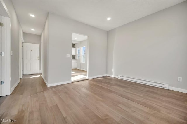 empty room featuring a baseboard radiator and light wood-type flooring