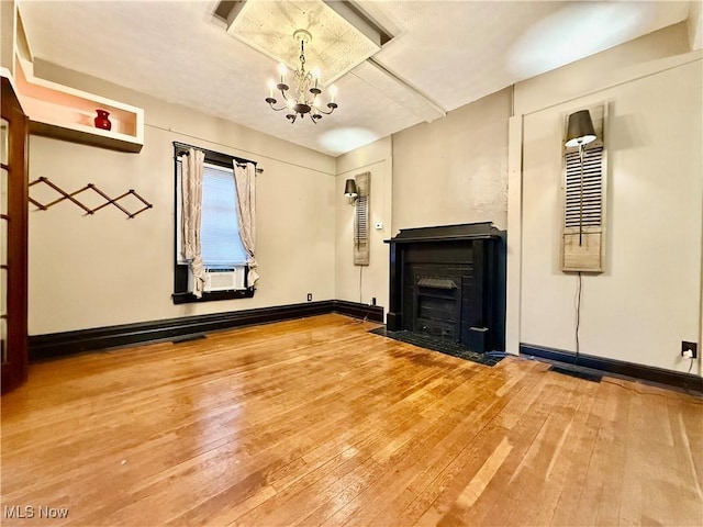 unfurnished living room featuring hardwood / wood-style flooring, cooling unit, and an inviting chandelier