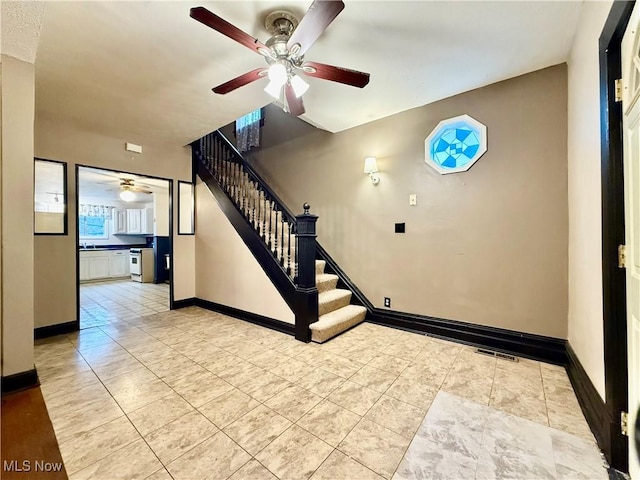 stairs with sink, tile patterned floors, and ceiling fan