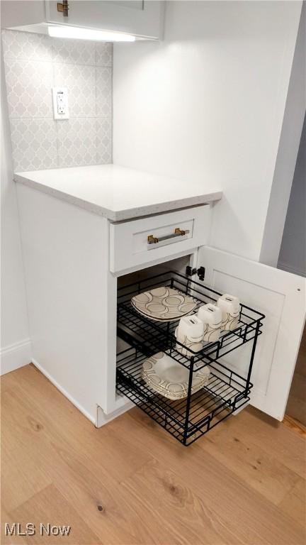 details with backsplash, light hardwood / wood-style flooring, and white cabinets