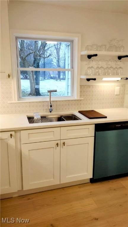 kitchen featuring sink, dishwasher, tasteful backsplash, light hardwood / wood-style floors, and white cabinets