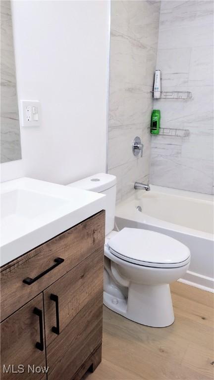 full bathroom featuring hardwood / wood-style flooring, tiled shower / bath, vanity, and toilet