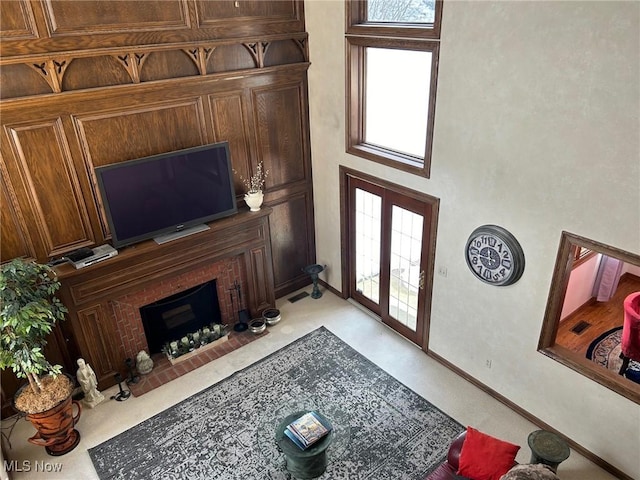 living room featuring a healthy amount of sunlight, a brick fireplace, baseboards, and french doors