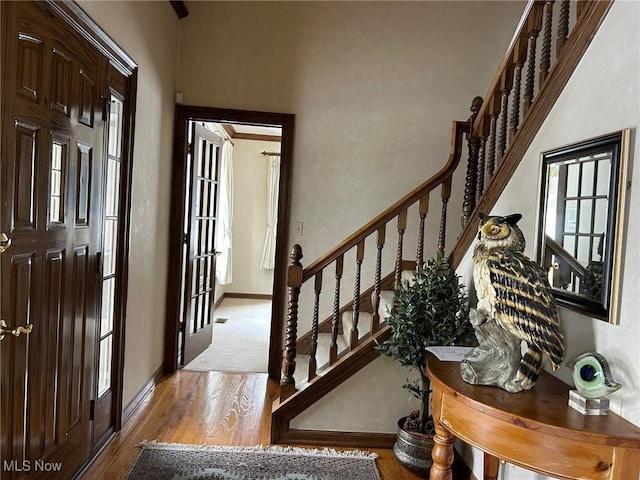 foyer featuring stairs, wood finished floors, and baseboards