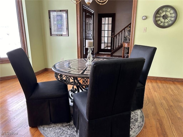 dining space featuring stairway, baseboards, wood finished floors, and an inviting chandelier