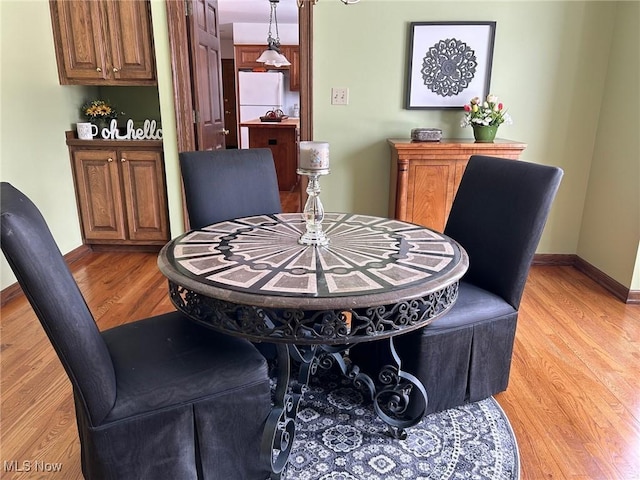 dining room featuring light wood-type flooring and baseboards