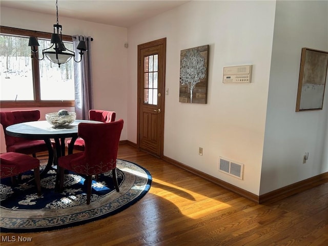 dining space with a notable chandelier, light wood-style flooring, visible vents, and baseboards