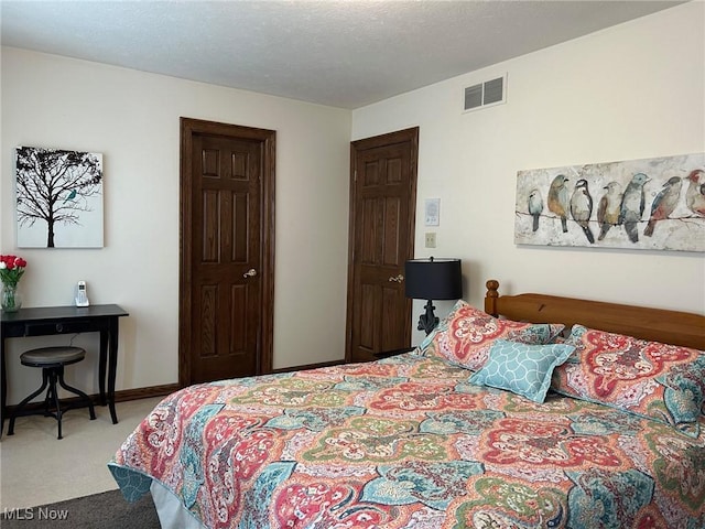 carpeted bedroom featuring a textured ceiling, visible vents, and baseboards