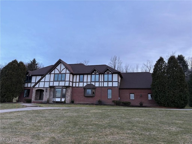 tudor house featuring a front yard and brick siding