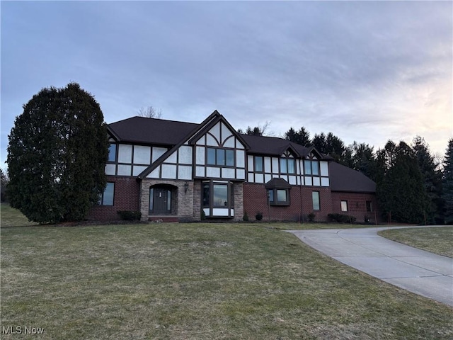 tudor-style house featuring a front lawn and brick siding