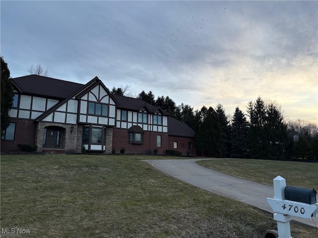 view of front of home with brick siding and a lawn