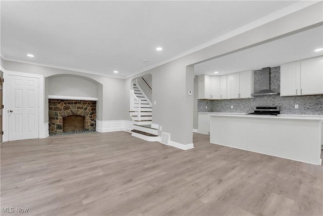 unfurnished living room with crown molding, a fireplace, and light hardwood / wood-style floors