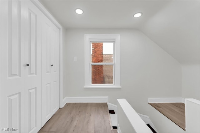 hall featuring lofted ceiling and light hardwood / wood-style flooring