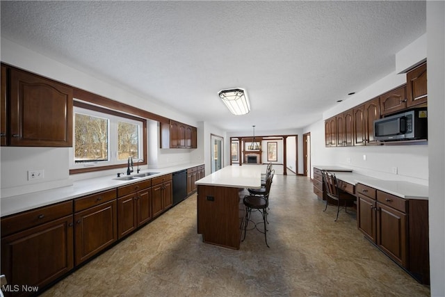 kitchen with sink, a center island, black dishwasher, built in desk, and decorative light fixtures