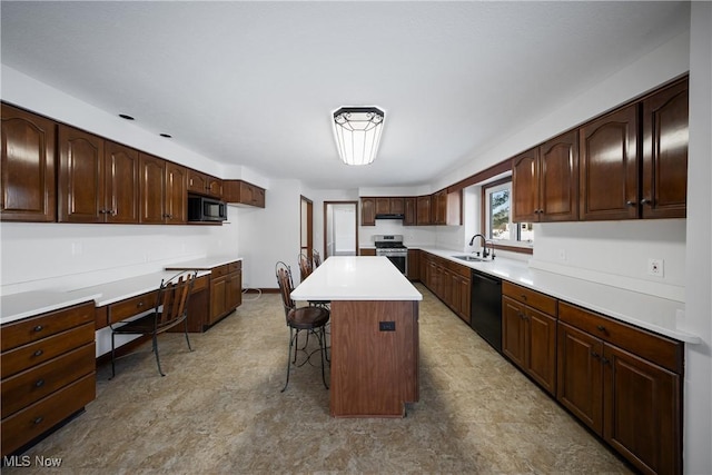 kitchen featuring sink, a breakfast bar area, built in desk, black appliances, and a kitchen island