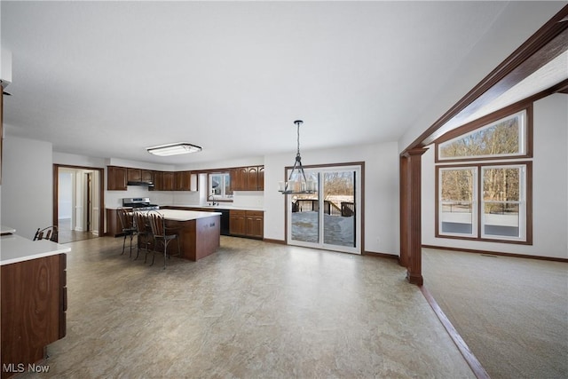 kitchen featuring a kitchen island, a breakfast bar area, hanging light fixtures, dark brown cabinets, and stainless steel range oven