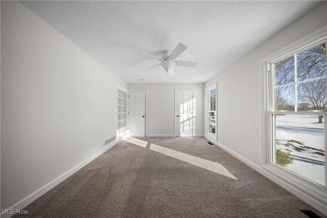 empty room featuring ceiling fan, a textured ceiling, and carpet