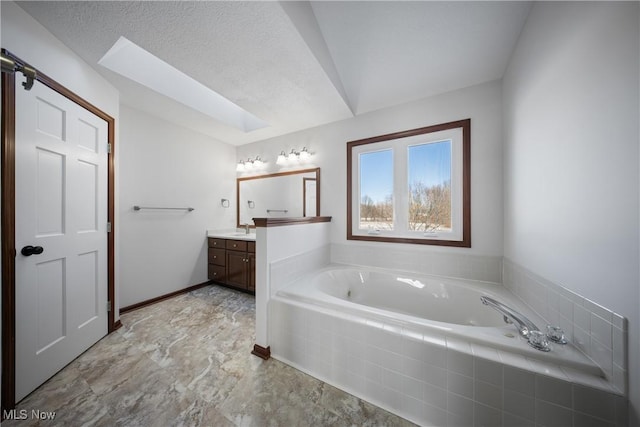 bathroom featuring vanity, tiled bath, and a textured ceiling