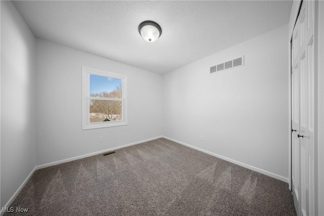 carpeted empty room featuring a textured ceiling